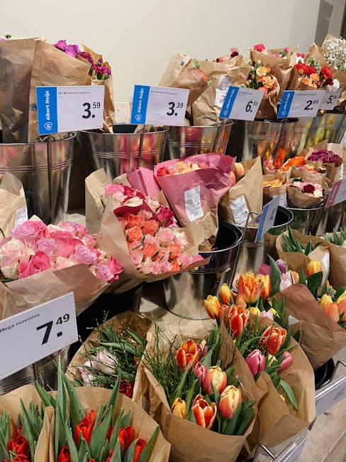 A display of various flower bouquets arranged in metal buckets at Notting Hill Florist. The bouquets include pink roses with delicate petals, orange and pink tulips with smooth, elongated petals, and