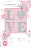 In this close-up of an anniversary card, the design radiates the soft intimacy of a private celebration at home in Notting Hill, where every detail is chosen with care. The focal point is the word LOVE, rendered in soft, raised glitter that forms each letter with clarity and gentle sparkle. The letter O is replaced by a shimmering, silver-textured heart that stands slightly proud from the surface, offering a pleasing tactile contrast to the smoother letters beside it. The palette around this motif is a harmony of pastel pinks and silvery greys: the central blush panel cradling the word LOVE sits comfortably on a paler pink background, creating a sense of depth without overwhelming the eye. Surrounding this, delicate floral illustrations unfold like blossoms in an English spring garden, their petals in blush and mauve tones that recall romantic roses and spring blooms gathered for an anniversary bouquet. Fine lines flow outward into curling vines, tiny petals, and airy swirls, with occasional subtle butterflies adding movement and an almost whimsical charm, as if they have just fluttered in from nearby Holland Park. The flowers have a soft, watercolor-like appearance, edges gently diffused, giving the card an almost hand-painted feel. Silver highlights appear here and there in the design, catching the light in a way that suggests evening candles on a Notting Hill dinner table. Framed within the card, the phrases On Our Anniversary and I love you today and always are written in refined, understated script, their gentle curves matching the organic flow of the vines. The result is a keepsake that whispers rather than shouts, perfectly suited to accompany elegant anniversary flowers delivered quietly to a cherished address in W11.